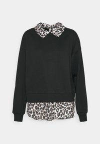 Svart långärmad sweatshirt lager på lager över en leopardmönstrad skjorta med matchande krage som sticker fram vid halsen och fållen.