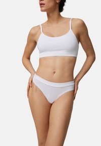 Bralette blanca de algodón con tirantes finos y un delicado ribete, combinada con bragas estilo hipster blancas a juego, que cuentan con una cintura suave y costuras mínimas.