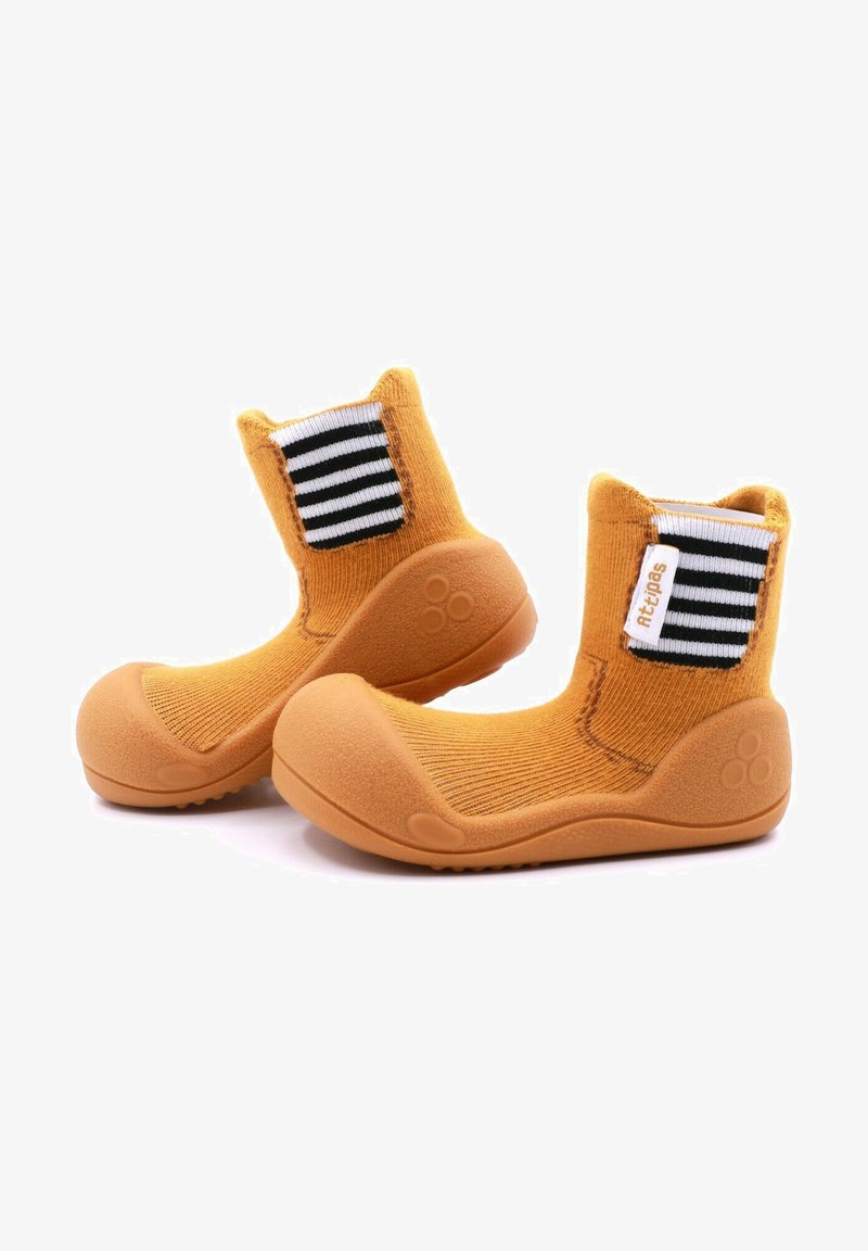 Botas de tobillo de tela amarilla con suelas de goma, acentos de tejido a rayas en blanco y negro, superficie texturizada y diseño de punta redondeada.
