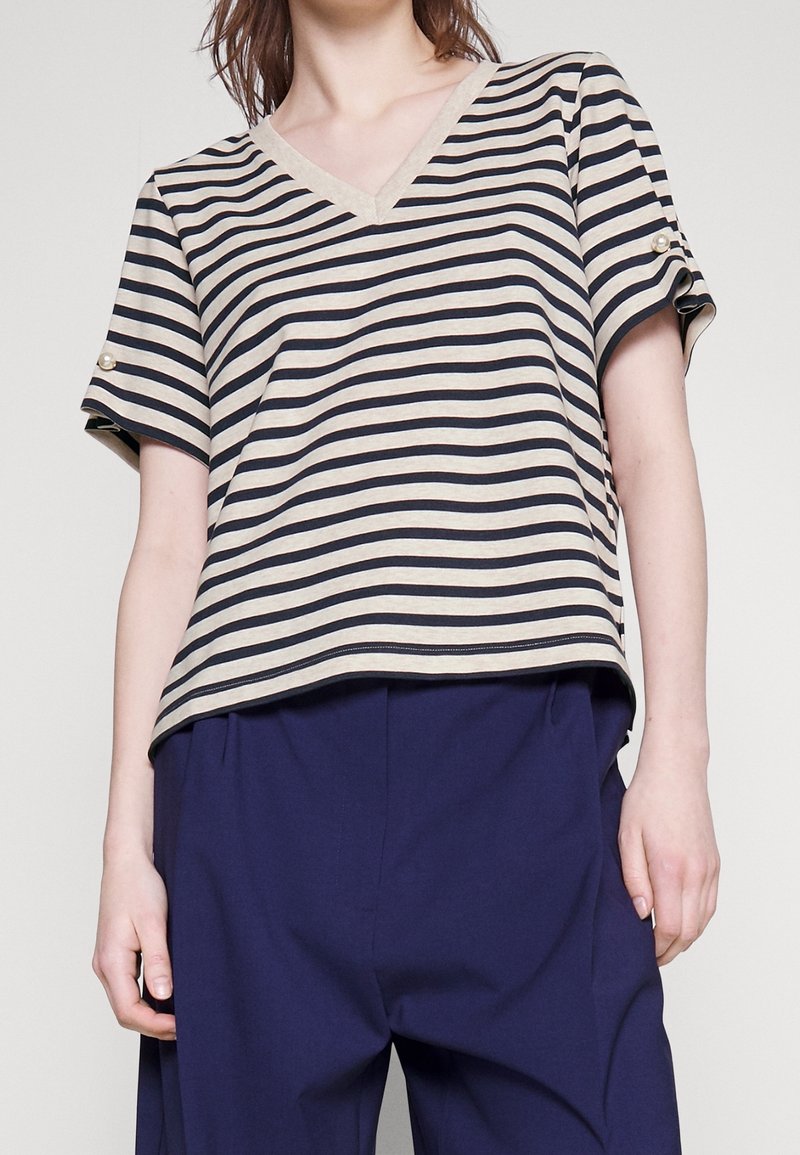Camisa de manga corta a rayas en beige y azul marino con escote en V, con un detalle de botones en las mangas y un corte relajado.