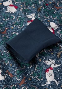 Cotton fabric featuring a dark blue background with cartoon animals. A smooth navy shirt cuff is partially visible, showcasing a textured pattern.