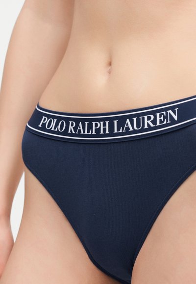 Κοντινό πλάνο ενός ατόμου που φοράει εσώρουχο σε σκούρο μπλε χρώμα με λευκή μέση που φέρει την επωνυμία Polo Ralph Lauren.