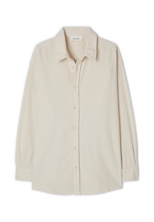 Beige corduroy-paita, jossa on pistekaulus, napitettava etuosa, pitkät hihat ja teksturoitu ribbikuvio.