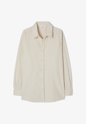 Bežs kordūras krekls ar punktveida apkakli, pogu aizdari, garām piedurknēm un strukturētu ribu rakstu.