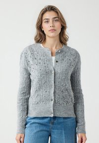 Grijze gebreide cardigan met een getextureerd kabelpatroon en decoratieve kralen, ronde halslijn en een knoopsluiting aan de voorkant.