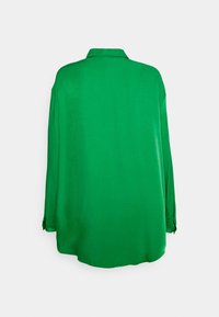 Blusa verde con una texture liscia, maniche lunghe e scollo con colletto. La vista posteriore mostra una vestibilità rilassata e un orlo arrotondato.