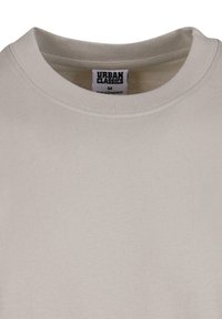 Svijetlo bež majica s kratkim rukavima, izrađena od mekanog pamuka, s rebrastim izrezom i oznakom s "URBAN CLASSICS" brendom.
