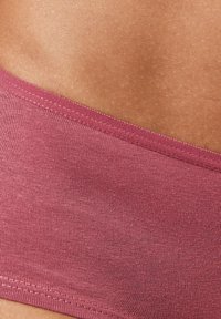 Fascia in tessuto borgogna senza cuciture con una texture liscia, caratterizzata da un bordo cucito piatto per il comfort. La vista ravvicinata rivela una finitura opaca e uniforme.