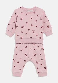 Ensemble bébé rose comprenant un haut à manches longues et un pantalon, décoré de petites imprimés de cerises rouges et de poignets côtelés aux manches et aux jambes du pantalon.