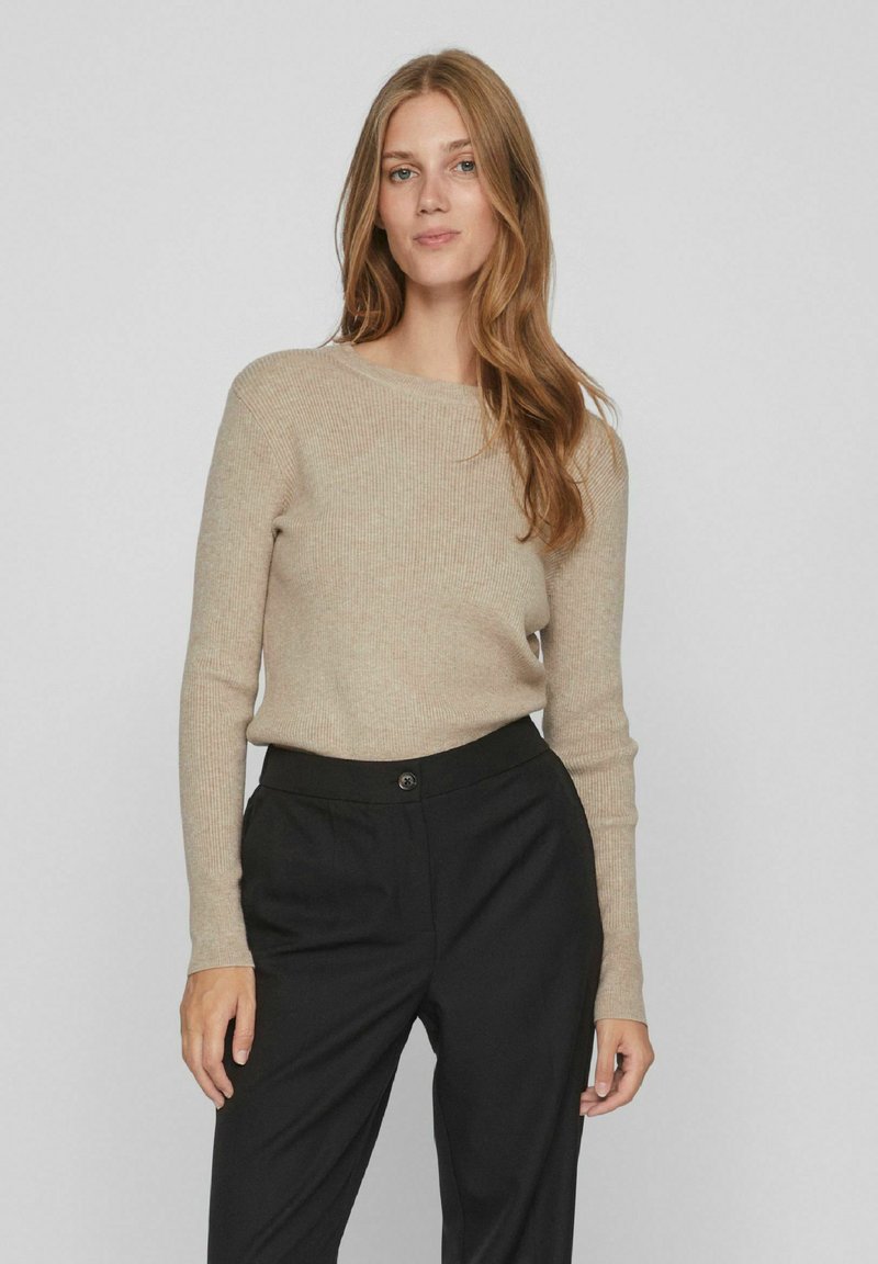 Pulover bej cu model cu nervuri, cu maneci lungi, decolteu rotund si textura moale, asortat cu pantaloni negri eleganti cu o singura inchidere cu buton.