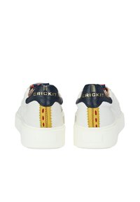 Sneakers bianchi con una parte superiore in tessuto texturizzato, tallone blu nano, logo "CRICKIT" dorato, cuciture decorative rosse e gialle sul retro e una suola chunky bianca.