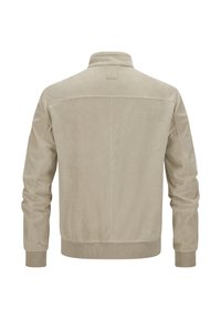 Beige Bomberjacke, strukturiertes Gewebe, gerippte Bündchen und Saum. Einfacher Kragen, glattes Rückenteil und ein kleines Etikett am Hals.