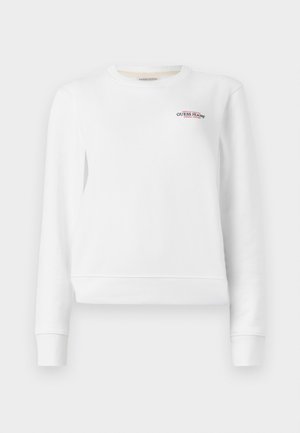 Balta sportinė maikutė su gipiūro rankovėmis ir apačia, priekyje turi mažą raudoną ir mėlyną siuvinėtą "GUESS JEANS" logotipą. Paprastas dizainas.