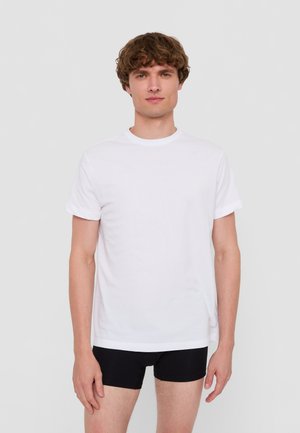 Witte katoenen t-shirt met een ronde hals en opgerolde mouwen, gedragen met zwarte shorts; gladde textuur en regular fit.