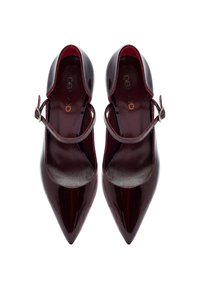 Tacones Mary Jane de charol burdeos oscuro, con punta afilada, tirantes alrededor del tobillo y hebillas plateadas, mostrados desde arriba sobre un fondo blanco.