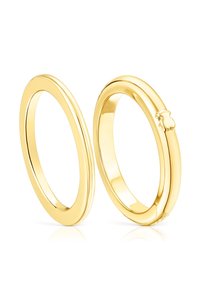Pierścienie w kolorze złotym o gładkiej, polerowanej powierzchni. Jeden z nich ma delikatne wcięcie jako detal, oba mają owalny kształt.