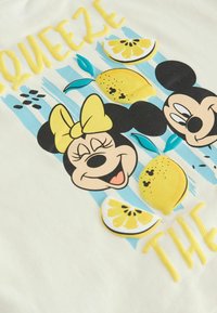 Mickey ja Minnie Mouse'i näod kollaste paeltega, ümbritsetud sidrunite ja sidruniviiludega hele sinise triibulise tausta peal.