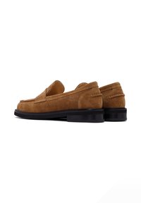 Mocassins en daim marron à finition lisse, avec un détail cousu sur le dessus et un petit talon en caoutchouc noir.