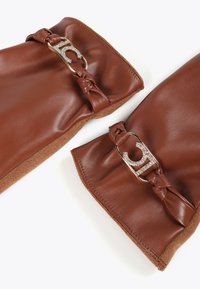 Bruna läderhandskar med mocka-pynt, knutdetaljer och en metallklämma dekorerad med rhinestones vid varje handled.