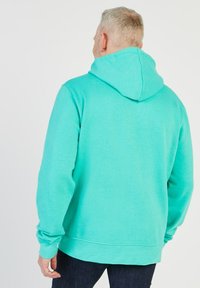Sweat à capuche turquoise avec un cordon de serrage, côtes aux poignets et à l'ourlet. Fabriqué en matière douce, présentant une texture unie et sans motifs visibles.