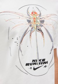 Λεπτομερής ανατομική απεικόνιση ενός λιβελούλη με διαφανή φτερά πάνω από την επιγραφή "Nike Running" και το λογότυπο Nike σε λευκό ύφασμα.