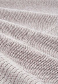 Sanftes rosa Strickgewebe mit einem strukturierten Muster aus horizontalen Rippungen und sichtbaren Nähdetails.