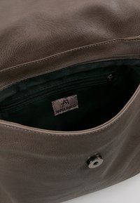 Borsa a mano in pelle marrone con una texture liscia, dotata di una tasca con zip e chiusura a scatto magnetico. Fodera interna di colore verde scuro. Etichetta del marchio visibile.