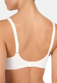 Witte bh van zachte stof, met verstelbare bandjes en haaksluiting. Heeft subtiele geschulpte details langs de randen en een gladde textuur.