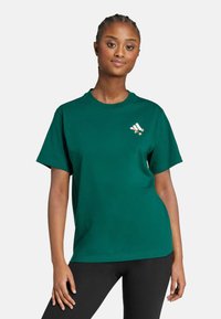 Camiseta de algodón verde con mangas cortas, cuello redondo y un pequeño diseño de logo en la parte superior izquierda. Textura suave con un corte relajado.