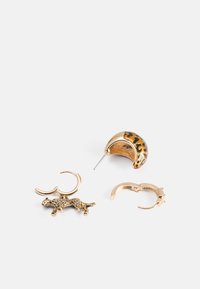 Tre paia di orecchini: un design leopardato dorato, un ovale lucido marrone e oro, e un semplice bracciale d'oro con chiusura.