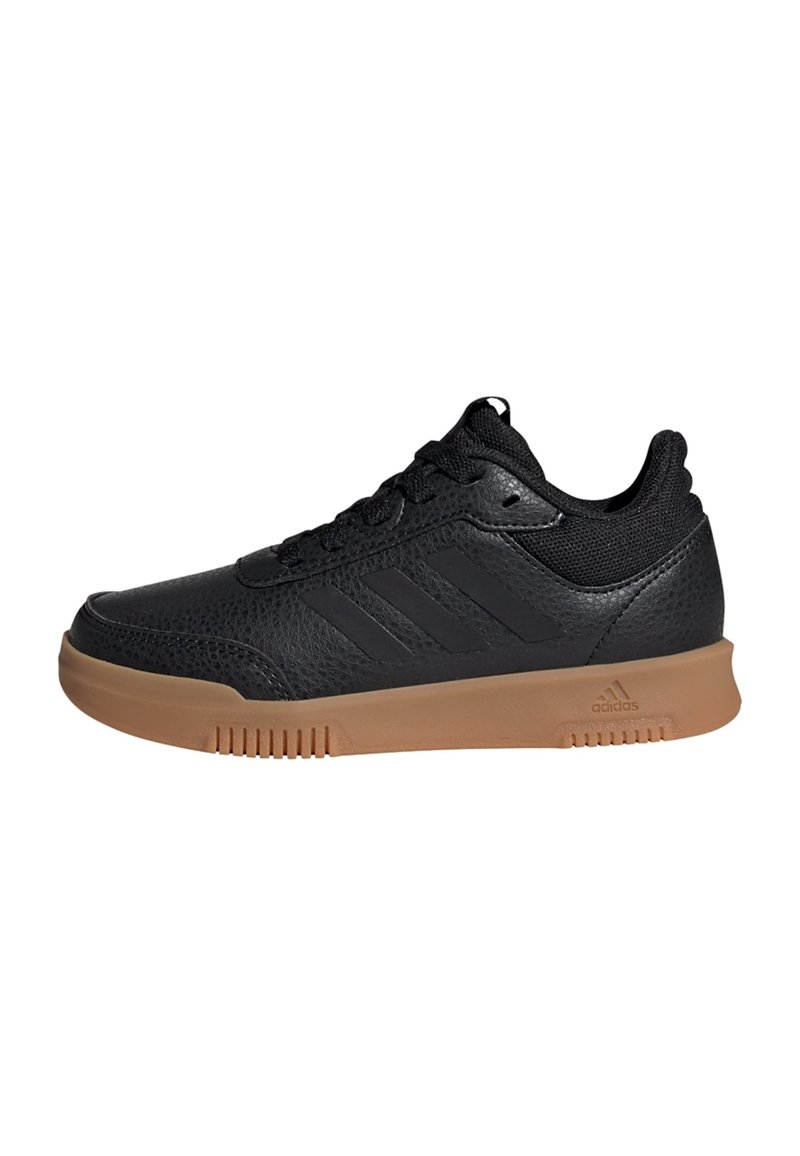 Sorte sneakers med en teksturert læroverdel, tre svarte striper på siden, og en tan gummisåle med horisontale spor.