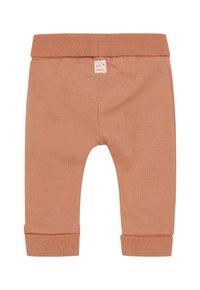 Zachte bruine babybroek met opgerolde boorden en een klein beige label met een eenvoudige kattengezicht en tekst op de voorkant van de tailleband.