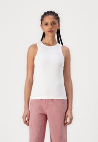 Weißes, geripptes Tanktop mit Rundhalsausschnitt, figurbetontem Schnitt und ärmellosem Design. Kombiniert mit rot-weiß gestreiften Hosen.