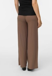 Brūni, platai kāju, ribota bikses, kas izgatavotas no viegla auduma, ar augstu jostasvietu un plūstošu dizainu, apvienotas ar melnu apavu.