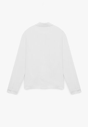 Camisa blanca de manga larga con un tejido texturizado, puños abotonados y un cuello clásico. La parte trasera presenta un diseño suave y minimalista.