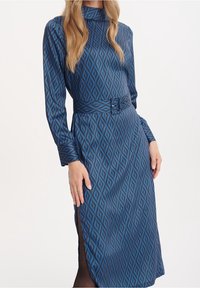 Sukienka z długim rękawem w niebieskim materiale z wzorem w diamenty, z paskiem w talii i bocznymi rozcięciami dla dopasowanego fasonu.
