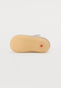 Kickers sko med gummisåle med teksturert mønster, en sølvfarget overdel og en rød prikk som aksent. Flat design som passer til hverdagsbruk.