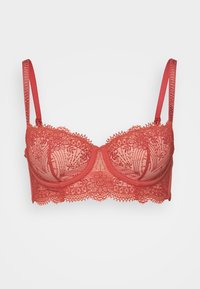 Soutien-gorge en dentelle corail avec armatures, présentant des motifs floraux complexes, un tissu transparent et des bretelles en satin réglables. Bords délicatement festonnés.