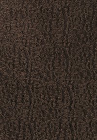 Tissu en dentelle marron avec des motifs complexes, une texture délicate et un design semi-transparent, créant un effet visuel superposé.