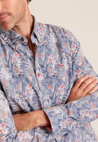 Bloemrijke overhemd met knopen, voorzien van een blauw en roze patroon van bladeren en bloemen, gemaakt van lichte stof, met rode accenten en een klassiek kraagontwerp.