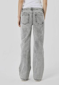 Jeans wide-leg in denim grigio con una texture sbiadita, dotati di cinque tasche e una vita standard, visti da dietro.