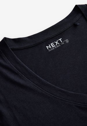 T-shirt noir en coton à col en V ample avec une texture lisse. Présente un large décolleté et une étiquette de marque discrète. Design à plat pour la présentation.