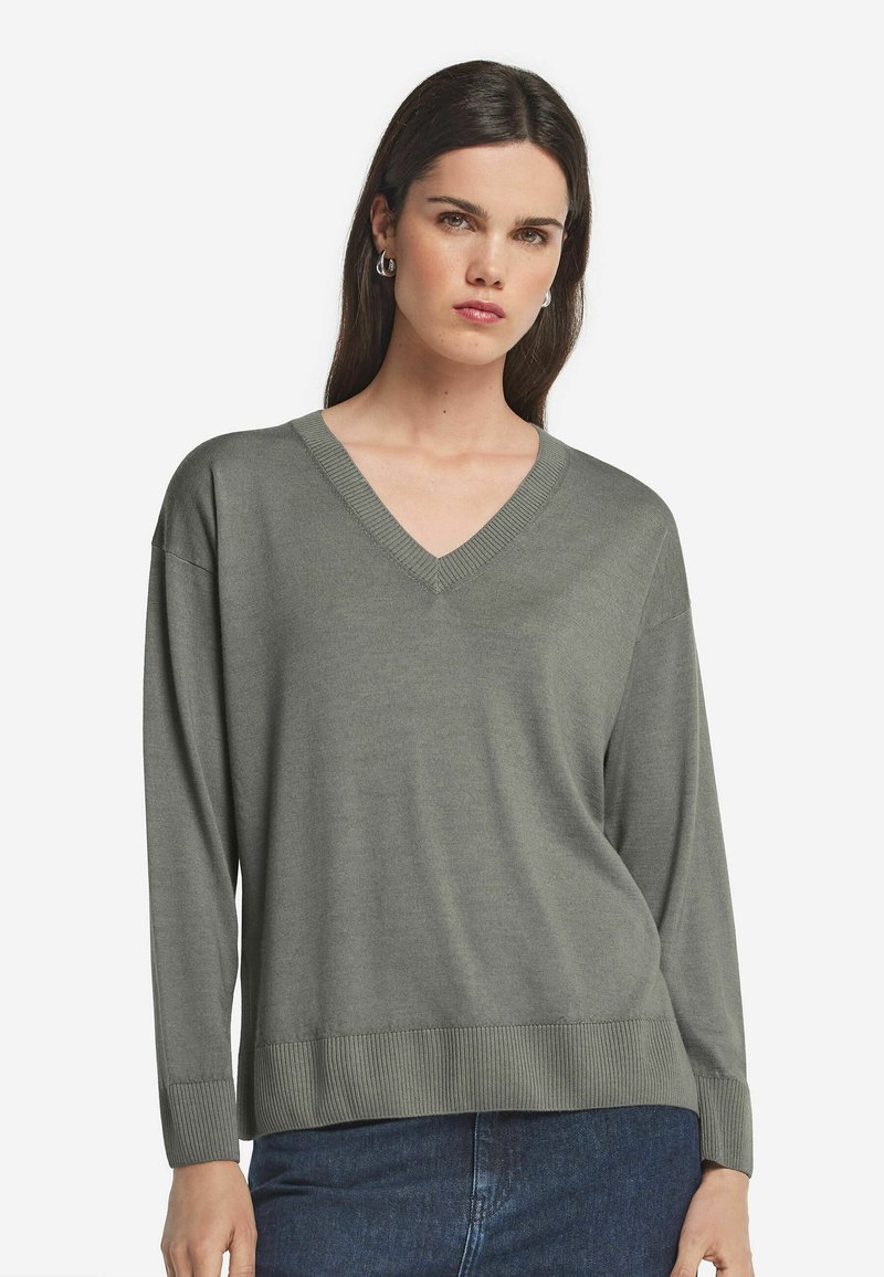 V-ringad tröja i olivgrön, tillverkad av mjukt material. Har långa ärmar och ribbad nederkant. Slät textur med en avslappnad passform.