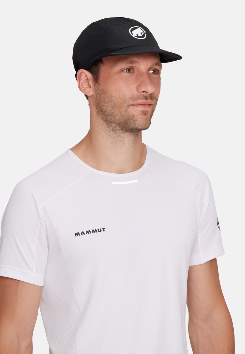 Casquette noire avec un logo, dotée d'une visière plate et de panneaux de ventilation. Associée à une chemise de performance blanche à manches courtes avec des détails réfléchissants.