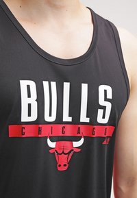 Débardeur sans manches noir avec le texte blanc en gras "BULLS" et "CHICAGO" sur une bannière rouge, accompagné d'un graphique de taureau rouge et du logo Adidas.