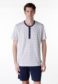 Set di pigiama da uomo con maniche corte, composto da una maglietta grigia a pois con colletto e bottoni blu navy, abbinata a pantaloni corti blu navy. Materiale in cotone morbido.