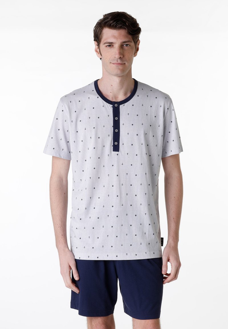 Set di pigiama da uomo con maniche corte, composto da una maglietta grigia a pois con colletto e bottoni blu navy, abbinata a pantaloni corti blu navy. Materiale in cotone morbido.