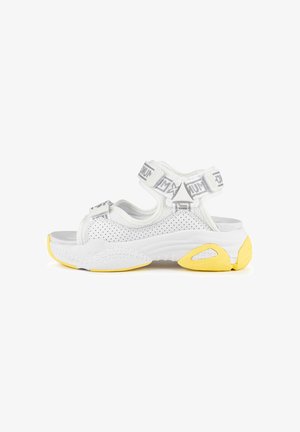Sandalias deportivas blancas con material de malla transpirable, correas ajustables y una suela de goma texturizada con acentos amarillos.