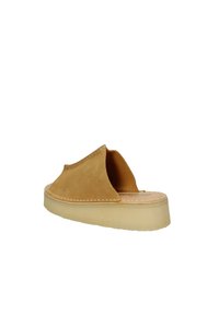 Scarpa slip-on in camoscio color sabbia con apertura sul retro, caratterizzata da una suola color beige chiaro e cuciture lungo il bordo superiore.