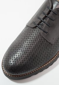 Chaussure en cuir tissé gris foncé avec un dessus lisse, un bout arrondi et un laçage ; présente une semelle marron contrastante avec des détails de couture.